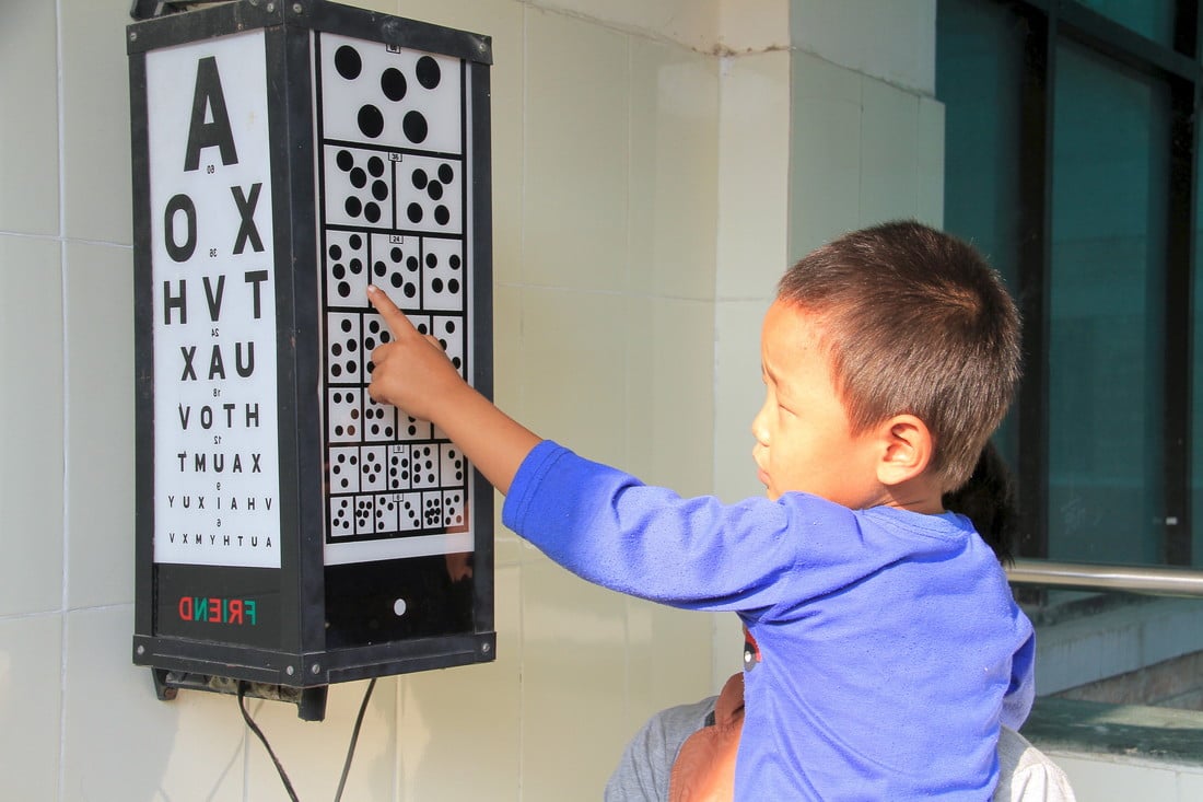 Sudip pointing to an eye chart on the wall