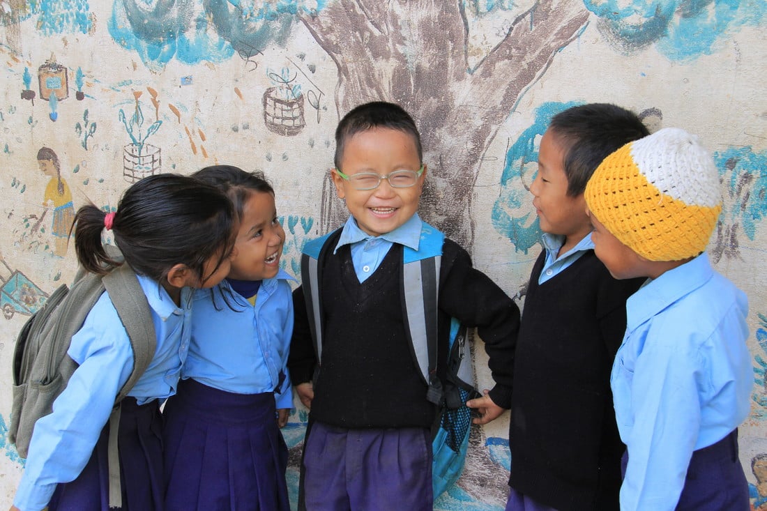 Sudip standing with his friends at school, as they admire his new glasses