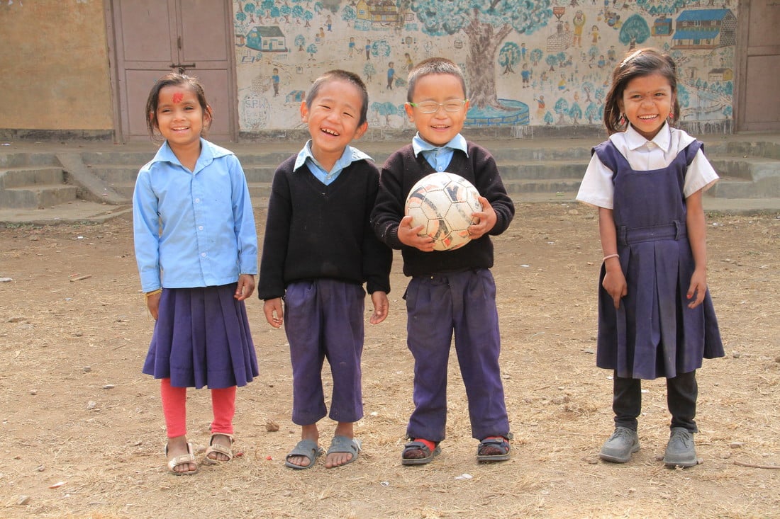 Sudip standing in the school playground with 3 friends, holding a football