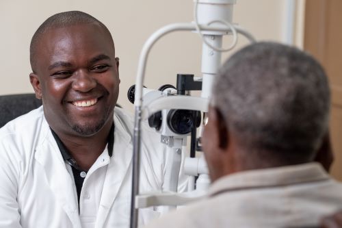 Dr Theophile Tuyisabe. examining a patient with cataracts