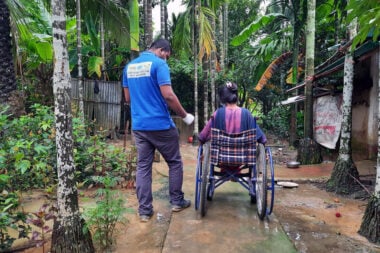 Tagari, is in her wheelchair. Next to her is a man in a blue t shirt with "Inclusive Emergency Response Team" on the back