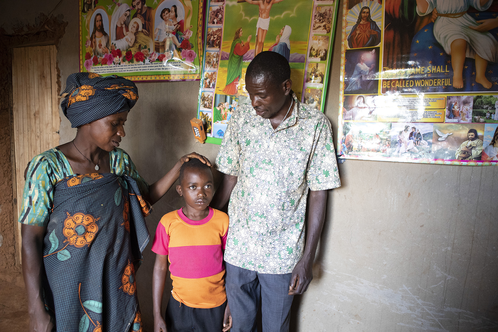 Etienne and his parents at their home. His mum has her hand on his head.