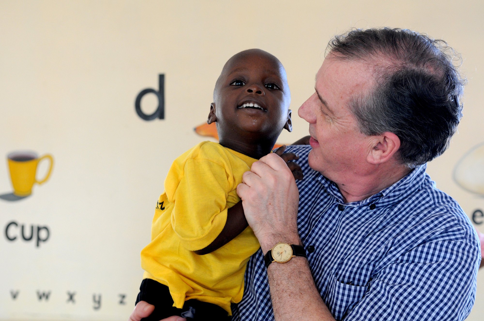 Prof. Dr. Allen Foster holding a child, visiting Manzese, Tanzania