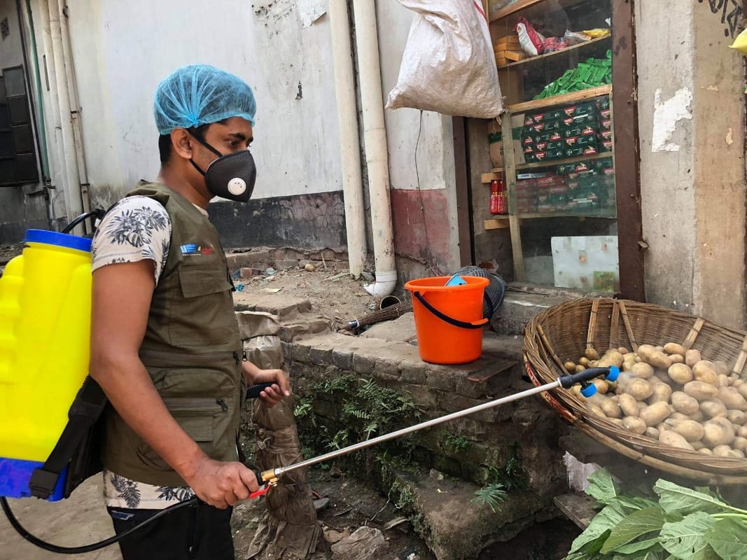 Man in PPE spraying disinfectant on market stalls