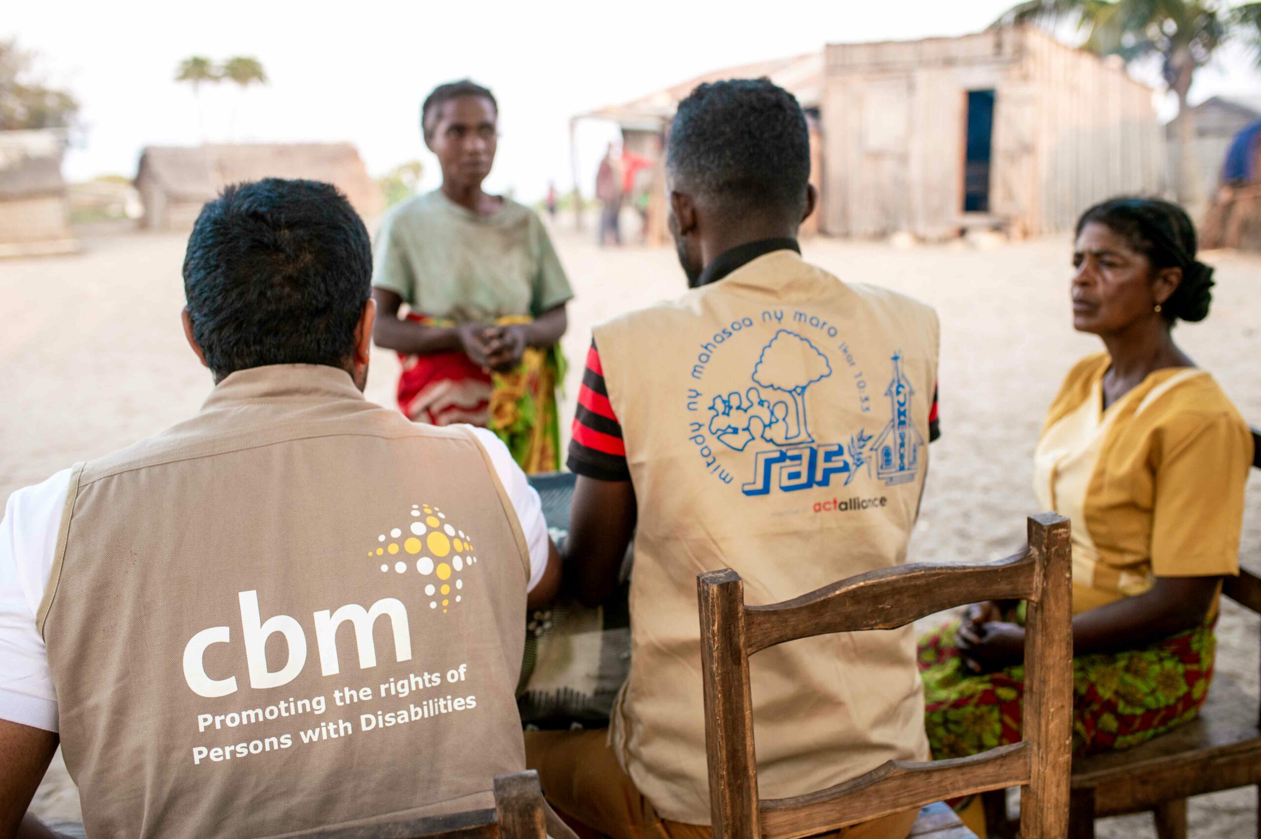 CBM and other local disability organisation members sitting at a table with their backs to the camera