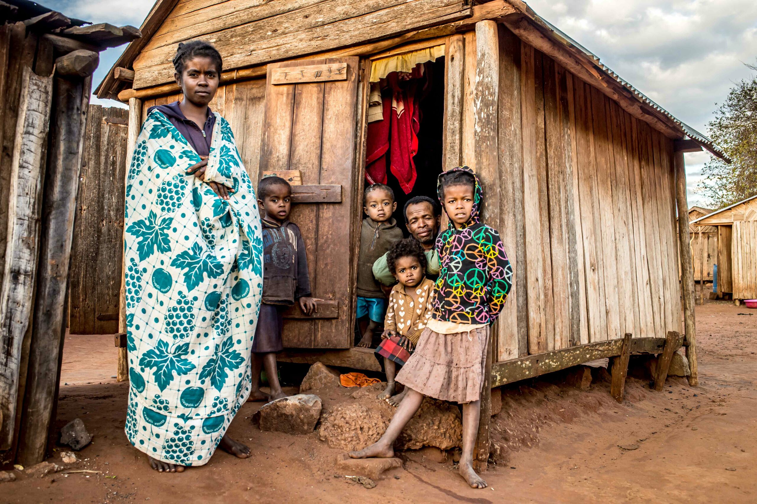 Family standing in front of their wooden hut