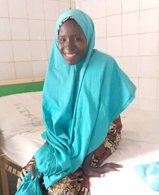 Barira sitting on the bed smiling to camera 