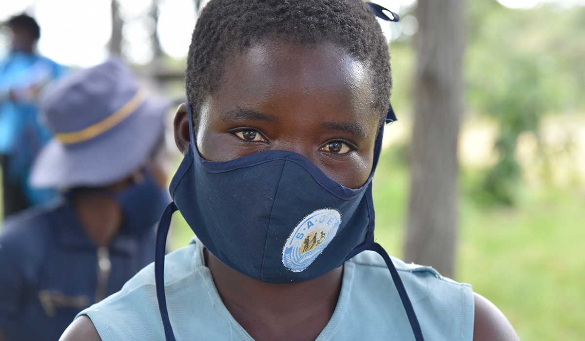 A young girl in Zimbabwe wearing a face mask and looking to camera