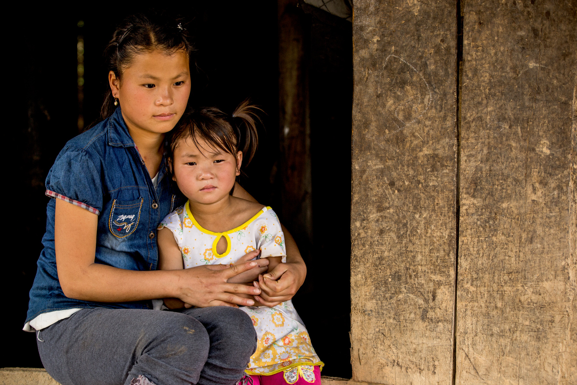 Nhung sitting outside her home with her sister La