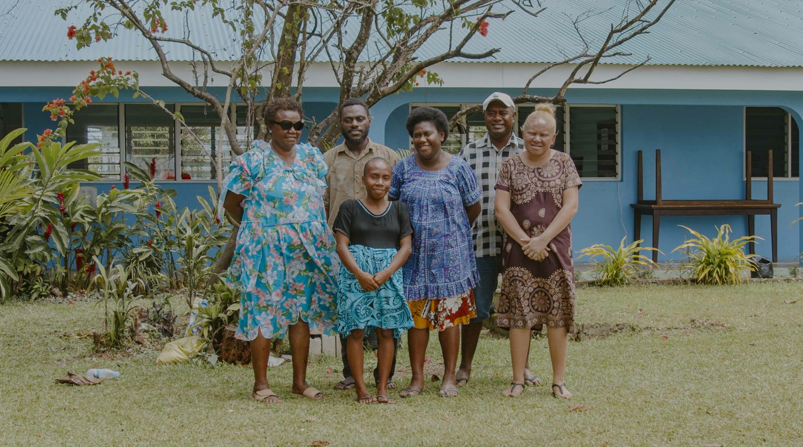 A group of women with disabilities in Vanuatu, stood outside in front of a tree.