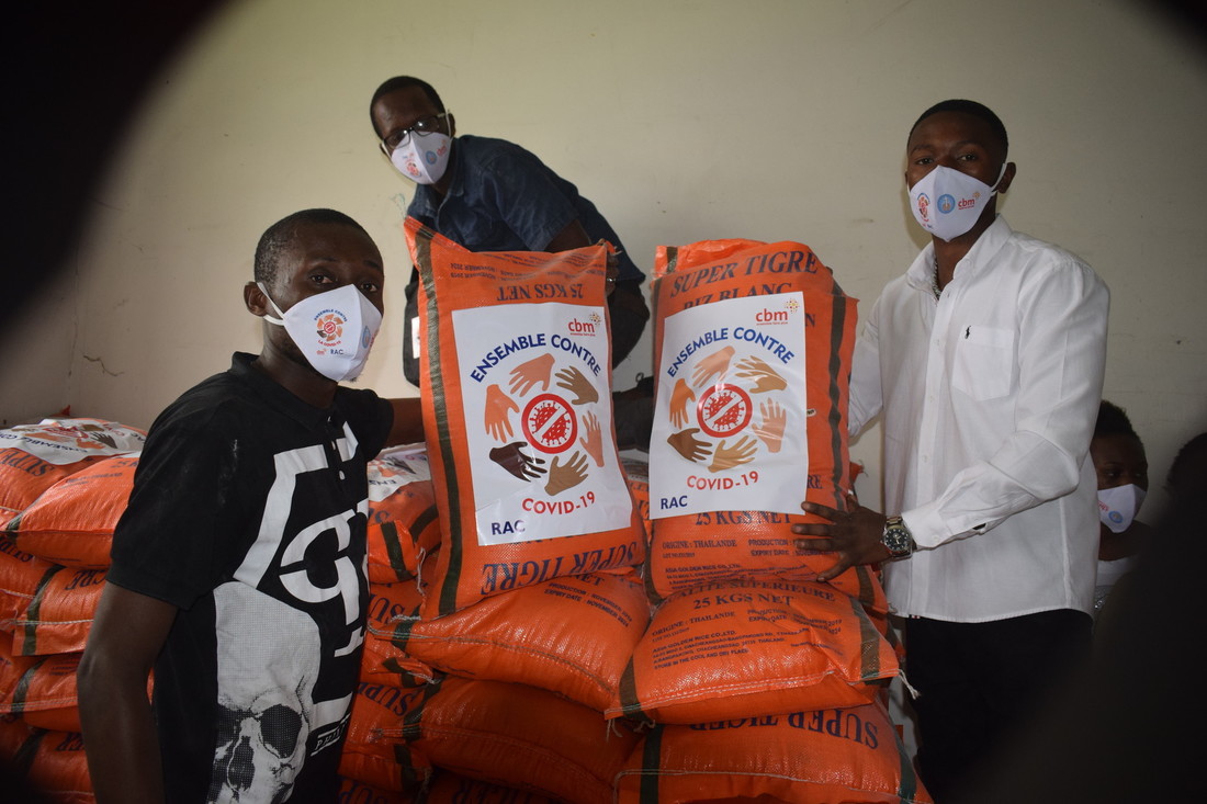 Three male volunteers wearing face masks and moving big bags of food