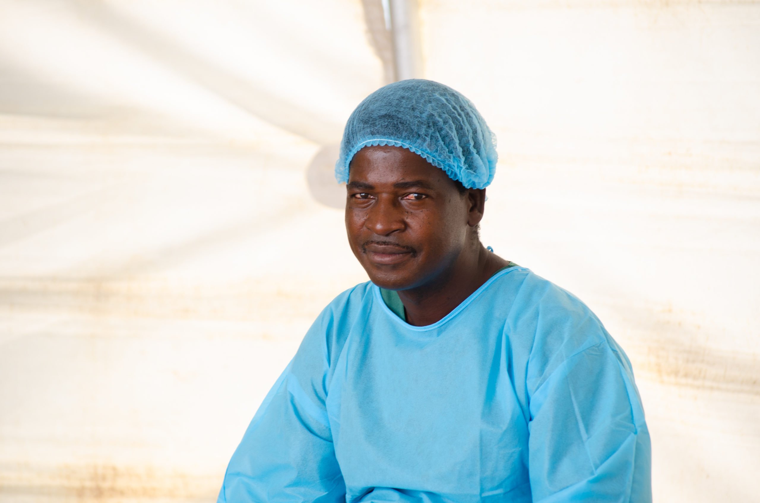 Godfrey dressed in blue doctors overalls and hair net.