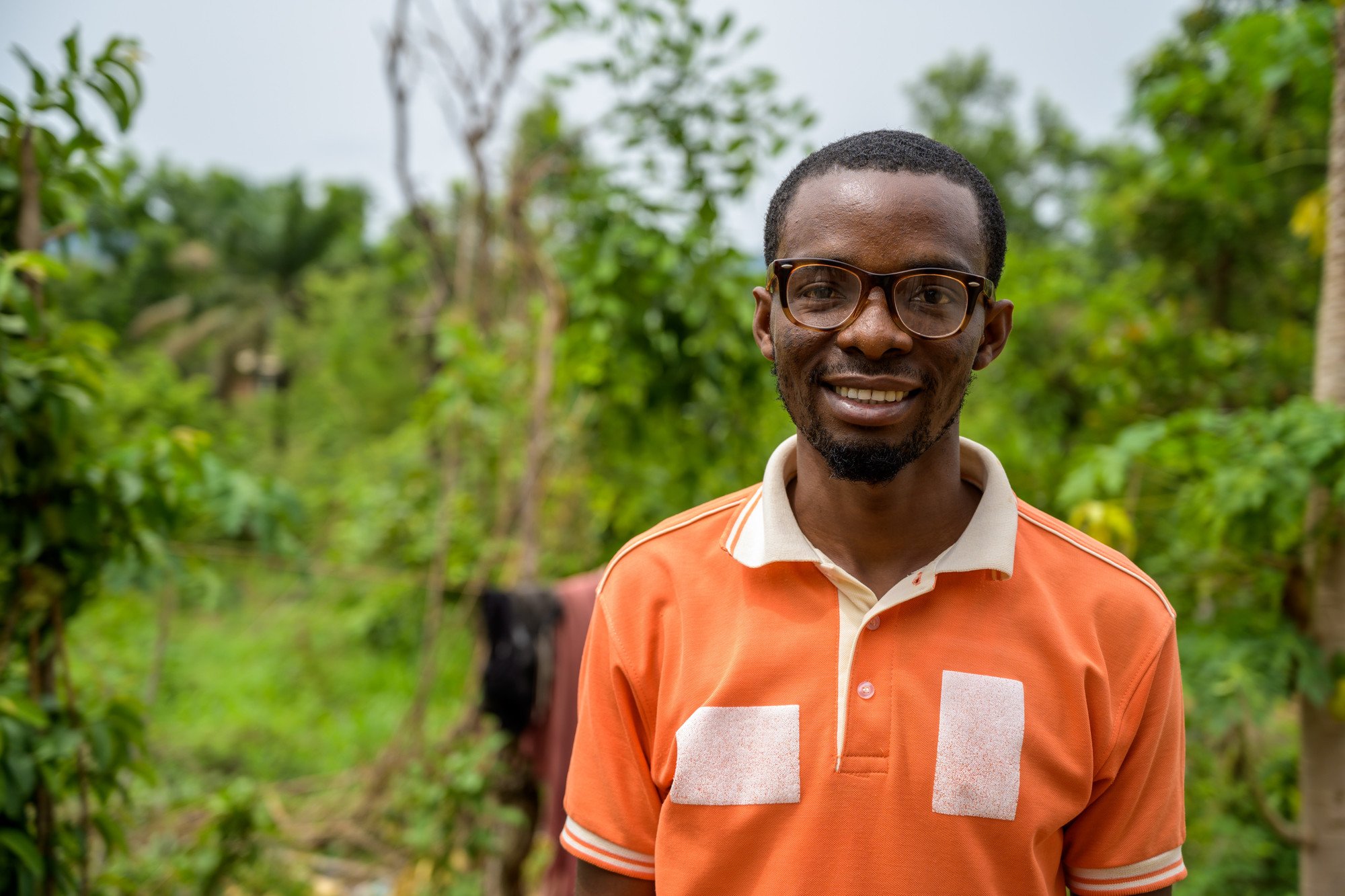 Close up of Samuel, smiling and standing outside.