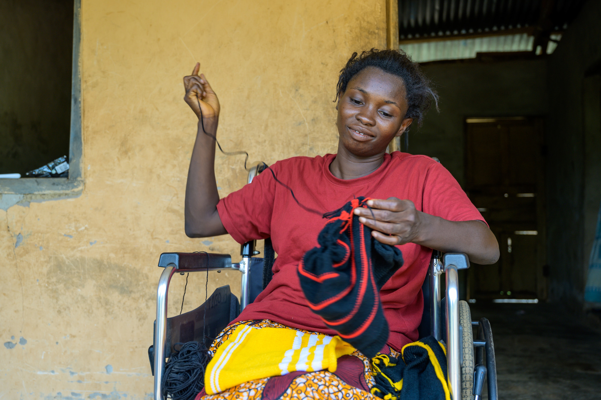 Blessing outside her home, sewing.