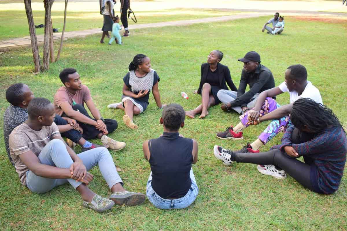 Students sat on the grass talking, in an outdoor safe space,