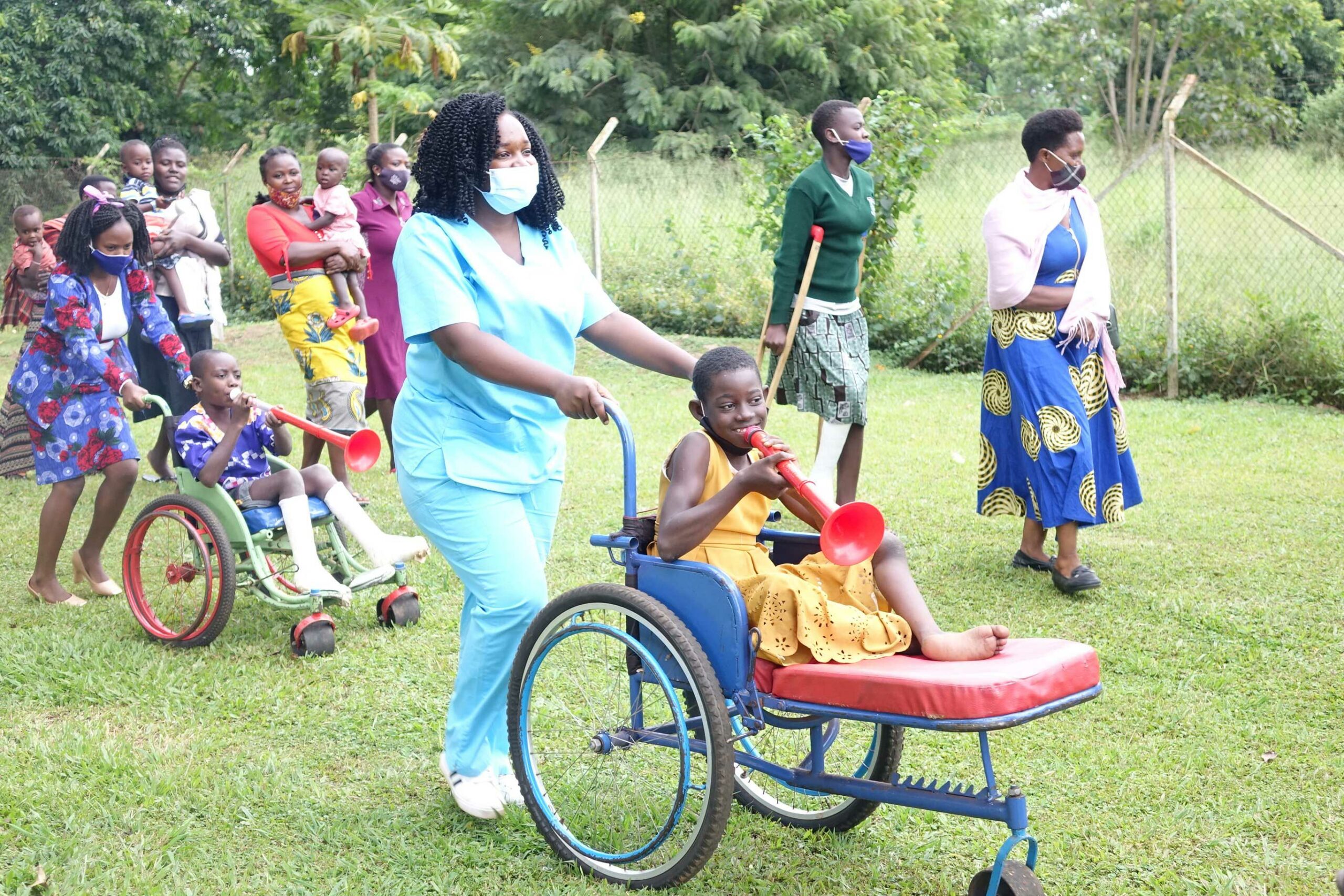 A nurse pushing a girl in a wheelchair, whilst she's playing a musical instrument.