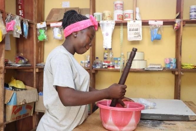 Faith is mixing ingredients in a pink plastic bowl. 