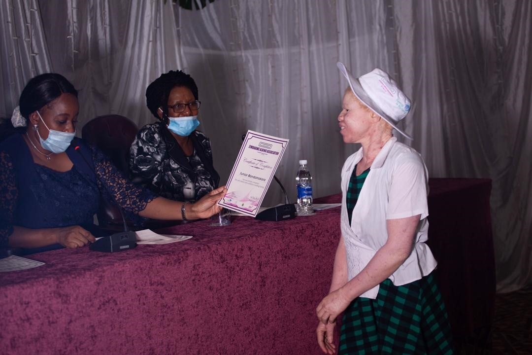 Girl with albinism being presented with certificates of completion in self-esteem and confidence building