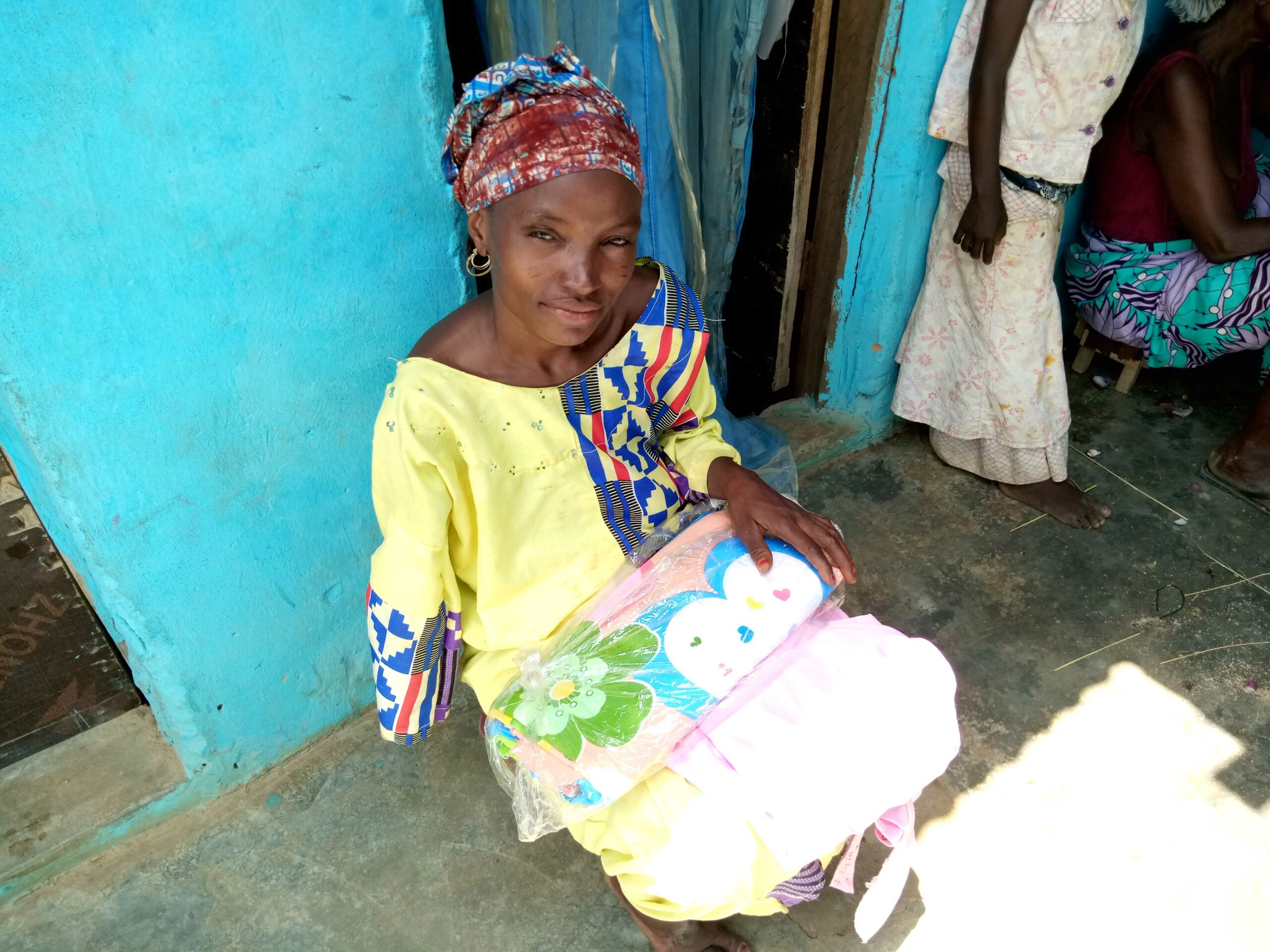 Hafsat sat down outside her home, holding some clothes she sells.