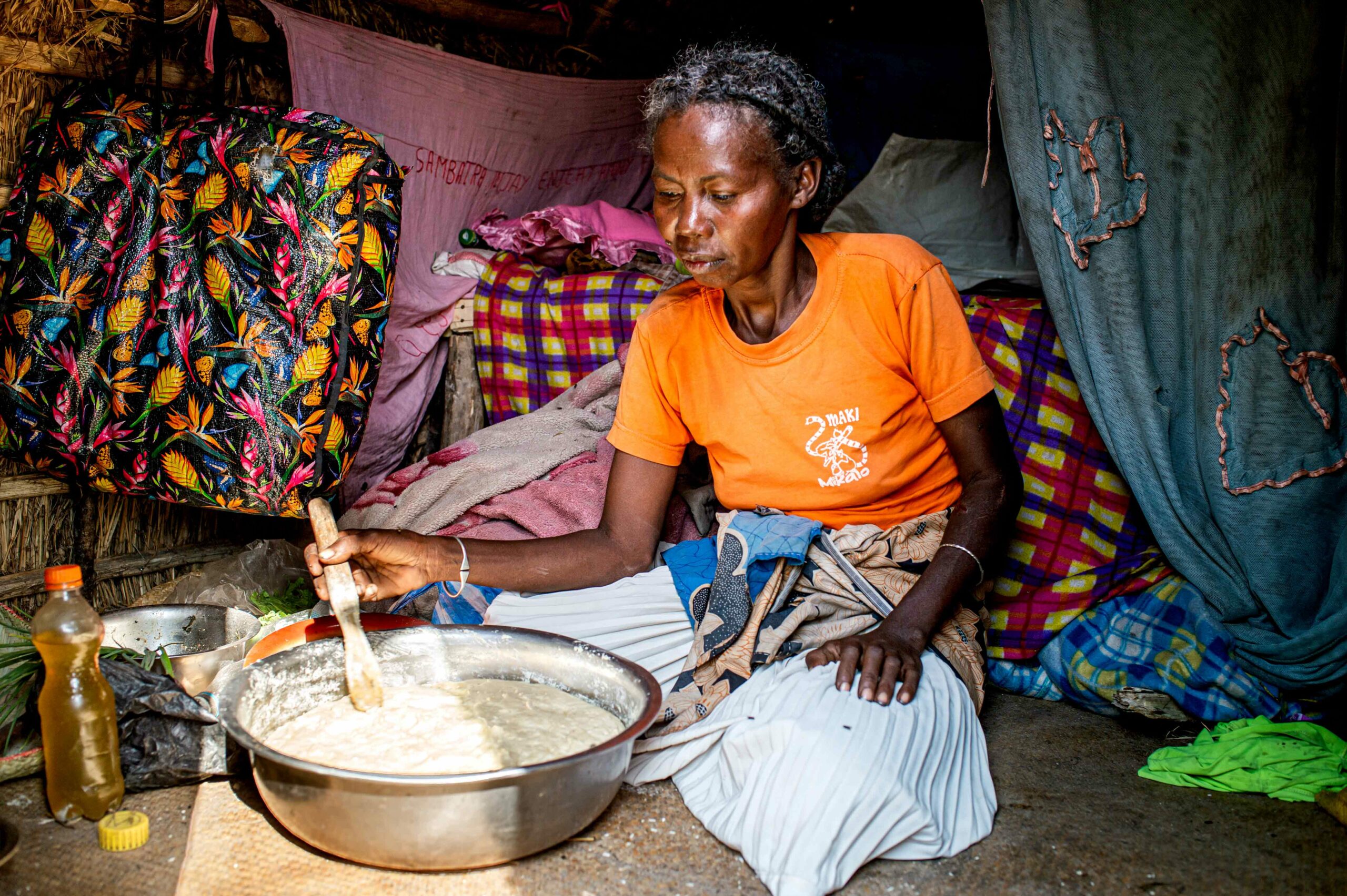 A women sitting stirring dough in a metal bowl