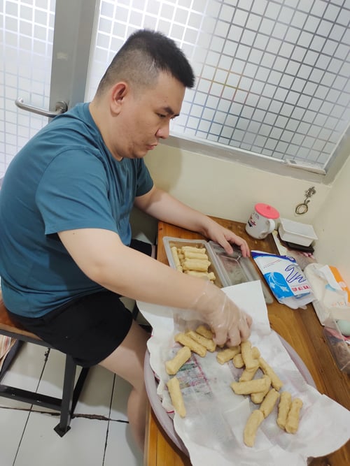 Hendry sits at a table preparing baked goods