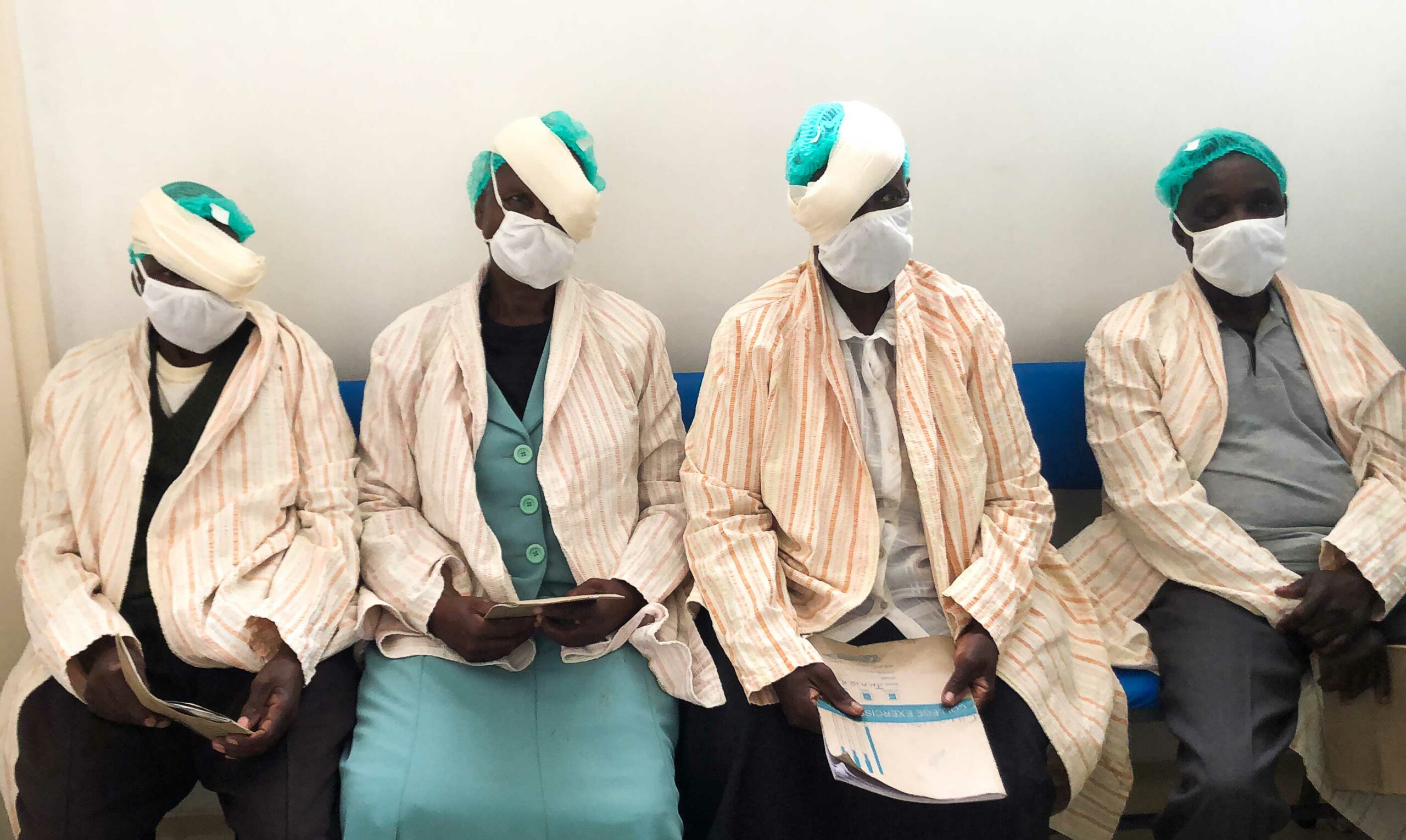 Four patients sat in a row, wearing eye bandages