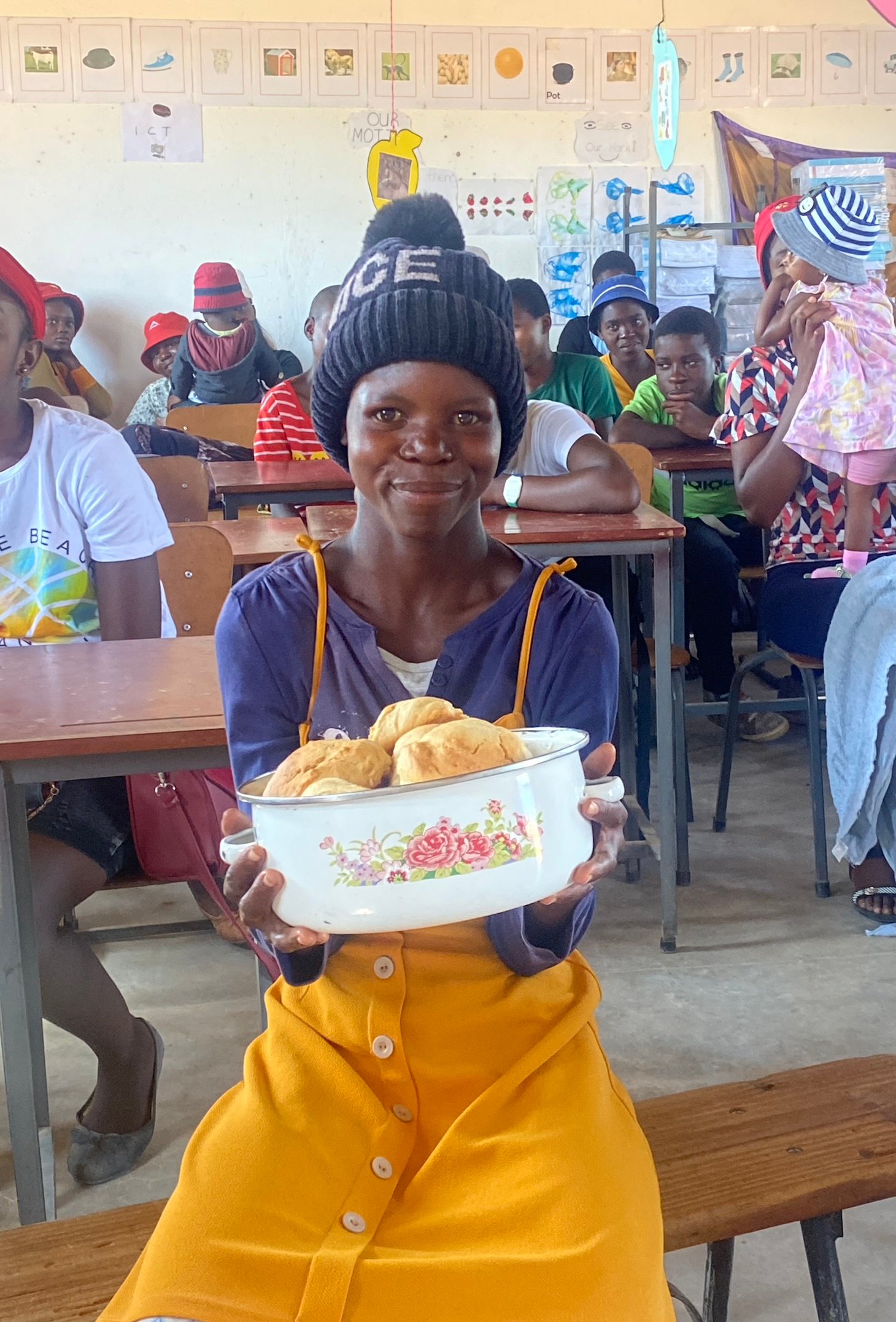 15 year old Nomazulu holds a dish full of scones and smiles. 