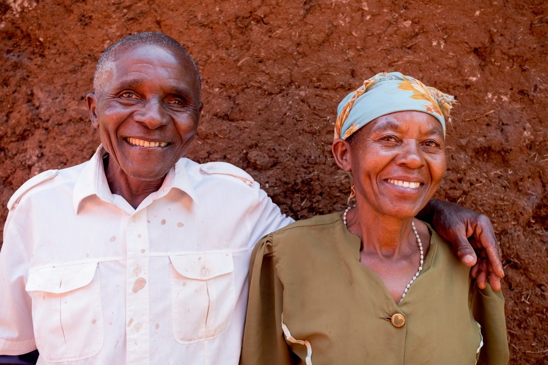 A man smiling and standing with his arm around a women next to him.