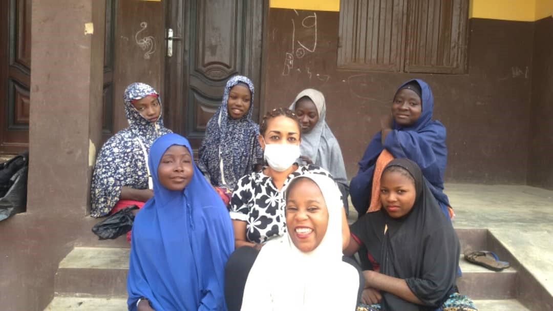 A group of girls with disabilities sitting on steps outside a building.