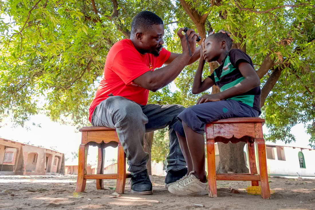 Jabes having his eye examined by a CBM health worker