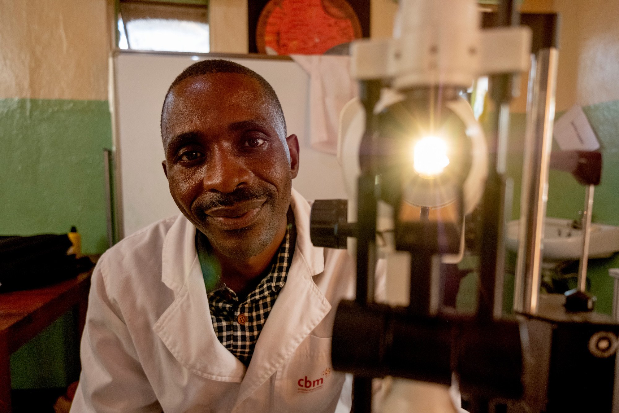 Male Ophthalmologist looking at the camera next to an ophthalmic machine with a bright light