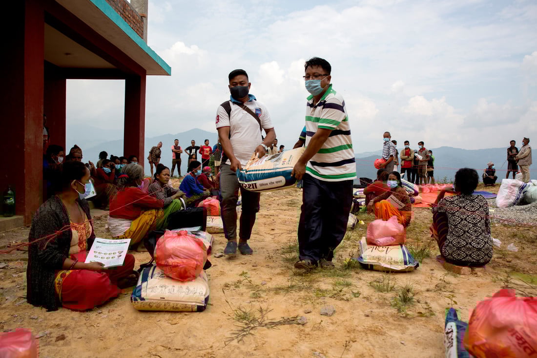 Two men carrying a huge food parcel between them, to give to a family in need.