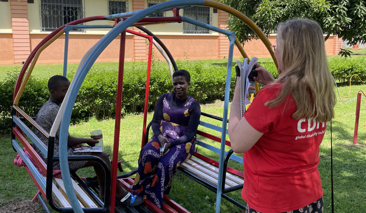 Theresa has got her back to the camera, wearing a CBM t-shirt in red. She is looking at two unknown patients from the hospital sitting on a brightly coloured play equipment.