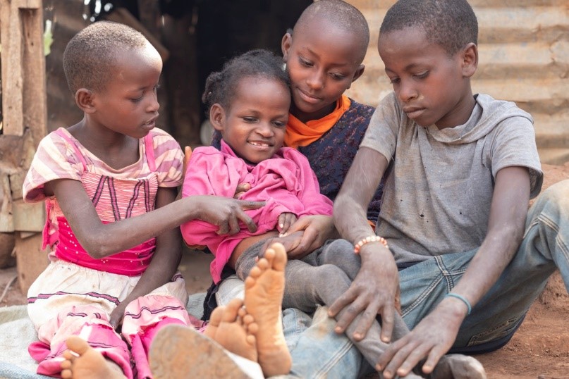 Risper is sat between her siblings, smiling.