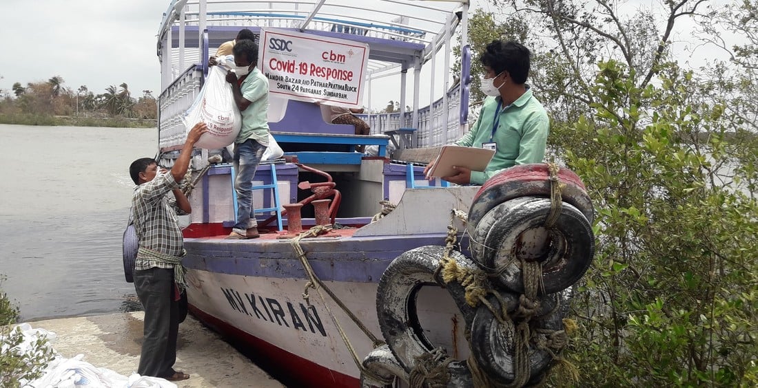 Four men offloading emergency aid parcel from a boat on the shore