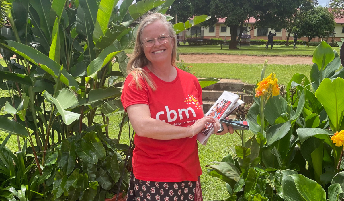 Theresa who is wearing a red CBM t-shirt is holding a CBM leaflet outside CorSU hospital.