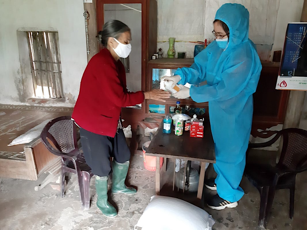 Female humanitarian worker offers hand sanitiser to a women inside her home in Vietnam 