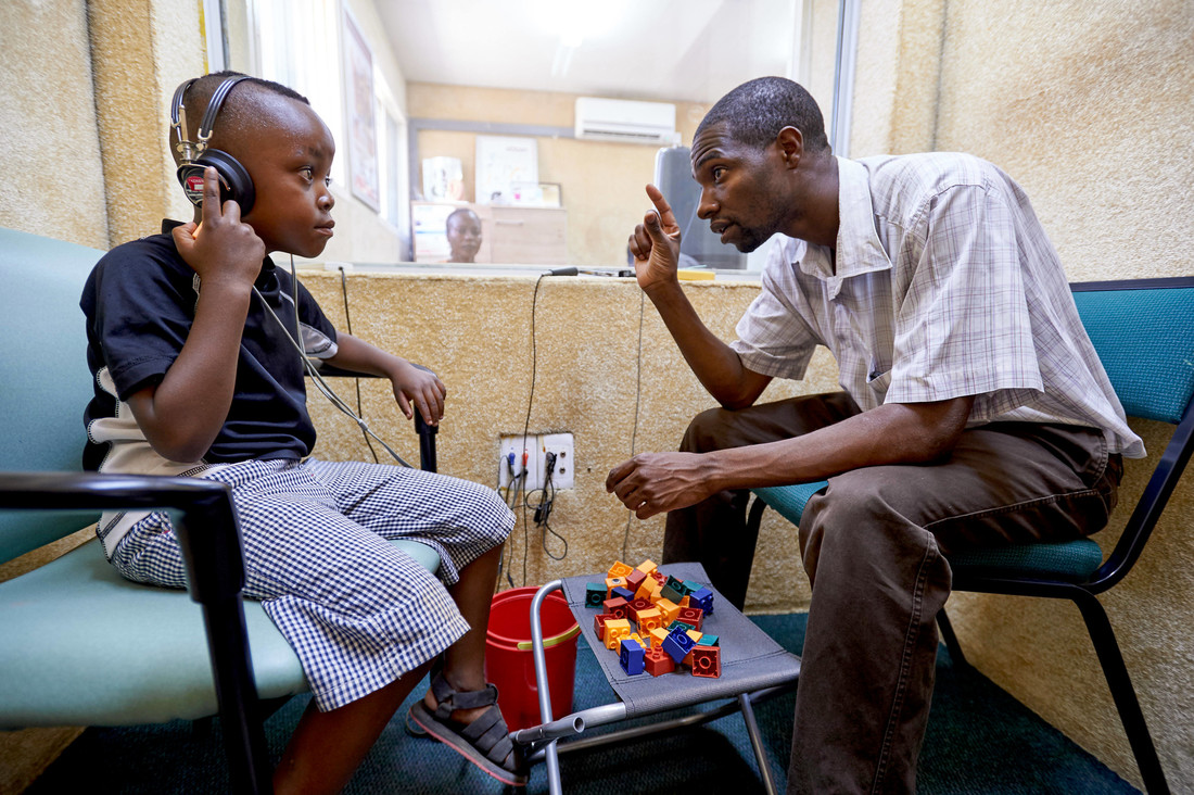 Edson (6) is doing a hearing test with Patson Sakala, hearing instruments specialist at Beit CURE Hospital in Zambia.