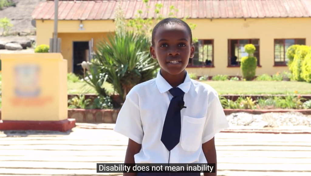 A video snapshot - Tinotenda stands infront of her school. "Disability does not mean inability" is subtitled.
