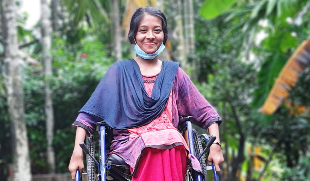A young woman sits smiling in her wheelchair