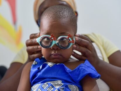 Nakisinde, wearing a blue dress, wearing a pair of glasses during an eye examination.