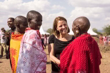 Kirsty smiling and shaking the hand of someone dressed in red. Two other people are stood next to her watching on.