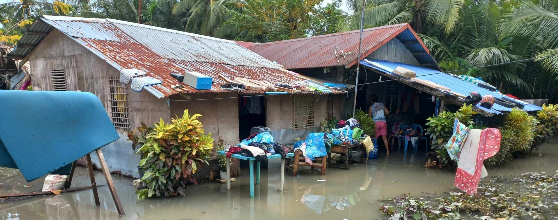 A flooded house with personal belongings hanging outside.