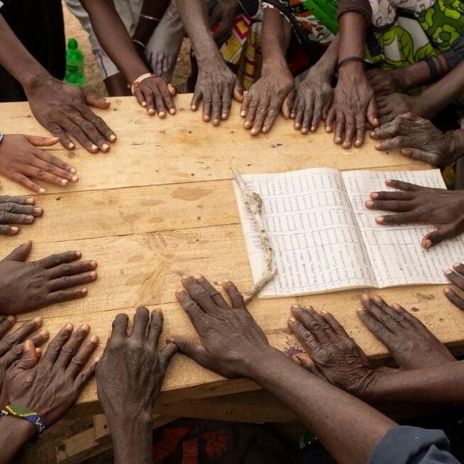 Lots of hands together on a table touching a document.