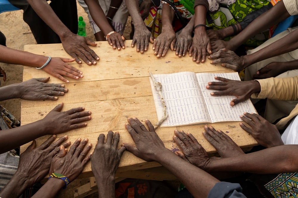 Lots of hands together on a table touching a document.