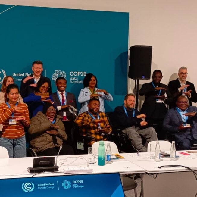OPDs, activists and disability-focused NGOs at COP29 attending the informal Disability Caucus meeting. Participants are making the equality sign.