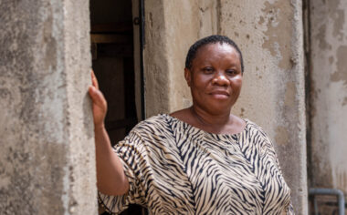 A woman in a zebra-print top, with her hand resting on a wall.