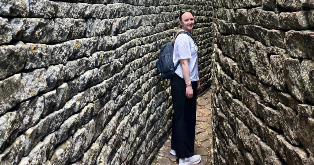 Emily standing in front of a brick wall, wearing a backpack.