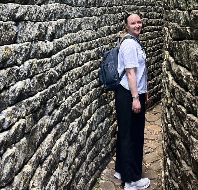Emily standing in front of a brick wall, wearing a backpack.