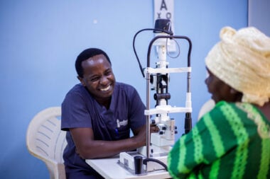 Mr Chege, wearing medical scrubs, smiles during an eye examination.